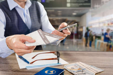 Male tourist with smartphone and tickets in his hands waiting for his planeの写真素材