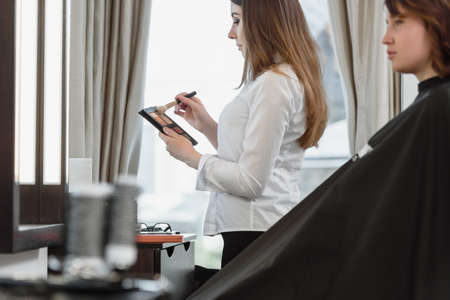 Professional visagiste doing makeup for beautiful brunette womanの写真素材