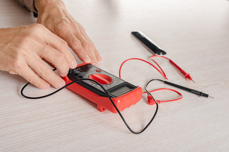 Closeup of man using multimeter for measuring voltage in electrical network