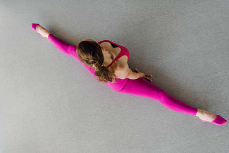 Beautiful flexible girl doing split exercise in gym, top view photoの写真素材