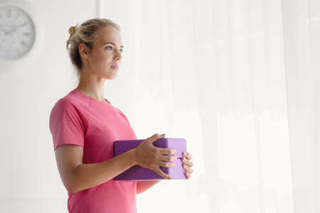 Portrait of smiling athletic blonde holding foam brick for trainingの写真素材