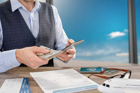 Closeup photo of male traveler with cash money waiting in airportの写真素材