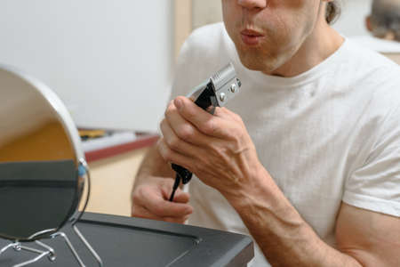Closeup of man cleaning electronic hair clipper after shavingの写真素材