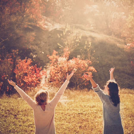 Two happy female friends enjoying golden autumn fall on sunny dayの写真素材