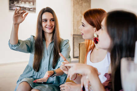 Young emotional girl talking with her best friends and gesturingの写真素材