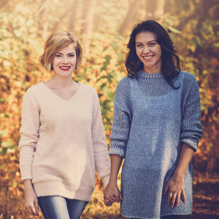 Beautiful happy women spending time together and walking in autumn parkの写真素材