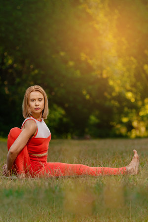 Young fit pretty woman having yoga training in summer park