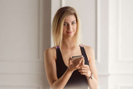 Attractive sporty woman resting after home fitness training and browsing internet on smartphoneの写真素材