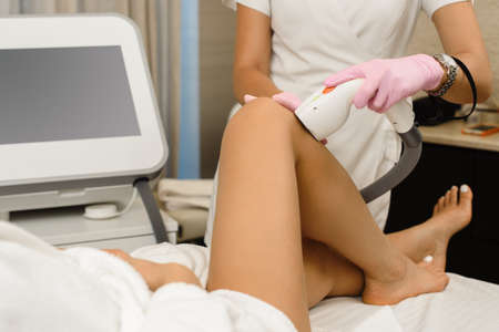 Professional beautician doing laser hair removal procedure for female client