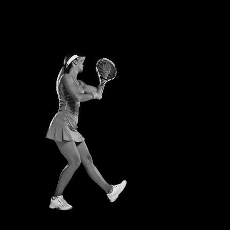 Fit professional sportswoman with tennis racket training on black backgroundの写真素材