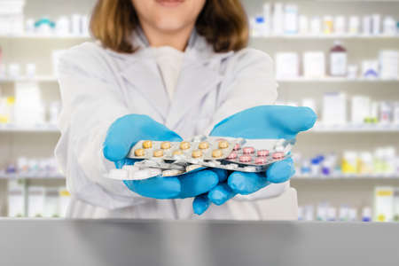 Female doctor pharmacist holding blisters of pills in handsの写真素材