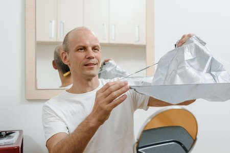 Adult happy man with hairdressing cape prepering for cutting hair at homeの写真素材