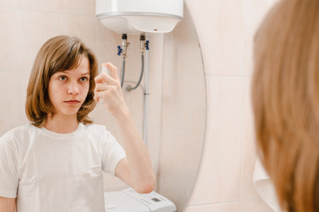 Young teen boy cleaning face with natural sprayの写真素材