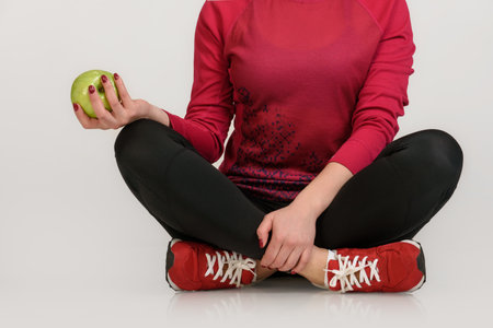 fitness woman in sport clothing holding green appleの写真素材