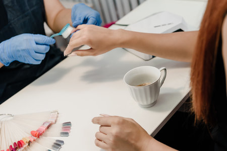 Hands of manicure master removing dust from nails with brushの写真素材