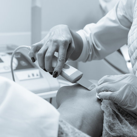 Closeup of female beautician doing ultrasonic skin exfoliation procedure for young woman