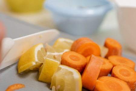 Closeup photo of man cutting fresh lemon and carrot while cooking nutrition breakfast for familyの写真素材