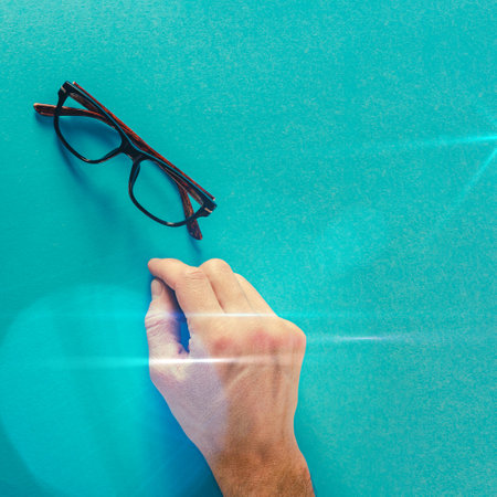 Closeup of man hand and glasses isolated on blue backgroundの写真素材