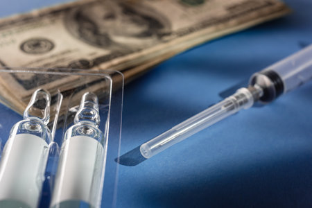 US currency money, ampoules and syringe for vaccination against virusの写真素材