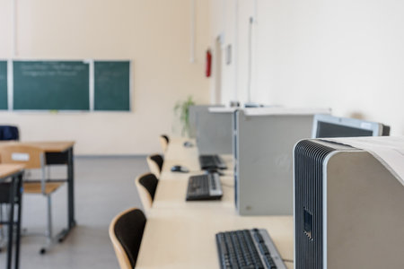 Empty modern classroom with chairs, desks, chalkboard and computersの写真素材