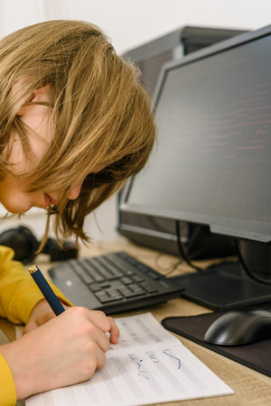 Concentrated teen boy with pen and music sheet studying at homeの写真素材