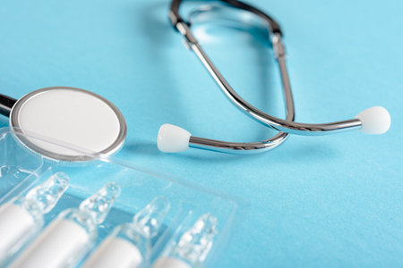 Closeup photo of stethoscope and ampoules with vaccines on blue backgroundの写真素材