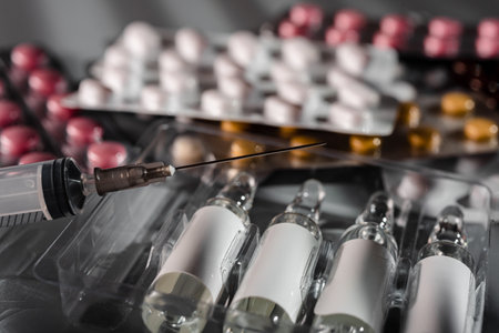 Medicine in vials, syringe ready for injection and pills on gray backgroundの写真素材