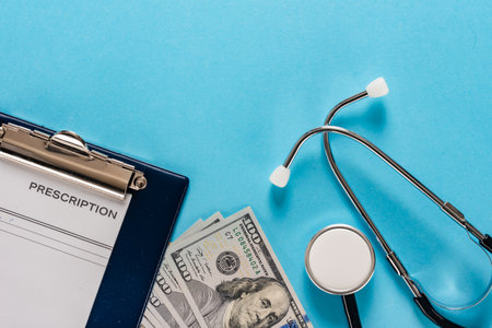 Blank prescription pad with form lying next to money and stethoscope on blue backgroundの写真素材