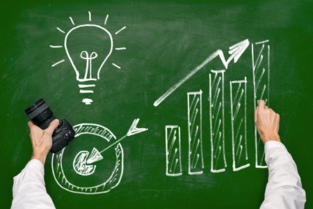 A man with a camera draws business efficiency growth schemes with chalk on a blackboardの写真素材