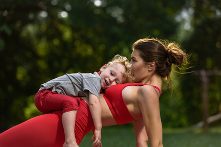Little boy having fun with his athletic sporty mother in city parkの写真素材
