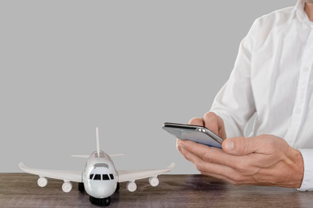 Male tourist in the studio on a light gray background interior traveling and using smartphone appの写真素材