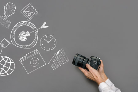 Man with professional camera against sketches of successful business on gray chalkboardの写真素材
