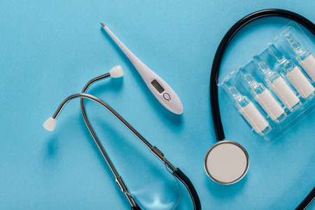 Collection of stethoscope, thermometer and ampoules with vaccine on blue backgroundの写真素材