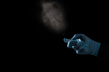 Spraying hands sanitizer to prevent epidemic virus spreading on black background