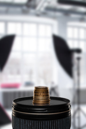 Modern digital camera lens and stack of coins in photo studio, stacked pile of coins, symbolizing the financial rewards and profitability associated with the art of photography.の写真素材