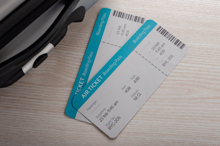 Boarding pass and airline tickets lie next to a suitcase on a wooden backgroundの写真素材