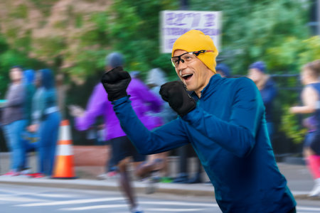 Portrait of happy successful amateur sportsman running on city street with raised hands, a jubilant and victorious rookie runner rushing down the city street with his arms raised triumphantly.の写真素材