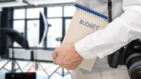 Male photographer counting and planning expenses for photo session in modern studio, the importance of financial planning in the world of photographyの写真素材