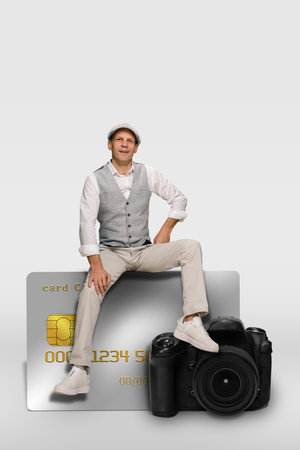 Young professional photographer working with online payment transaction via credit card, Radiant young man seamlessly fusing finance and visual art on contemporary camera.の写真素材