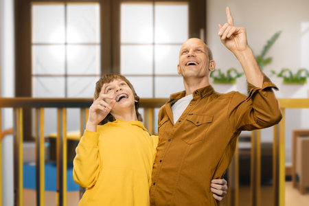 Portrait of happy smiling young father and teenager son spending time together at home, A joyful embrace: Fathers smile radiates as he supports and hugs his grateful teen son.の写真素材