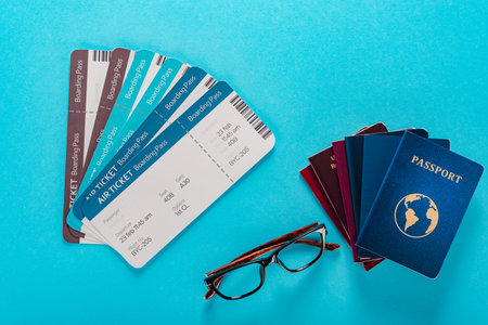 Summer travel planning with travel items air tickets passports and eyeglasses on blue backgroundの写真素材