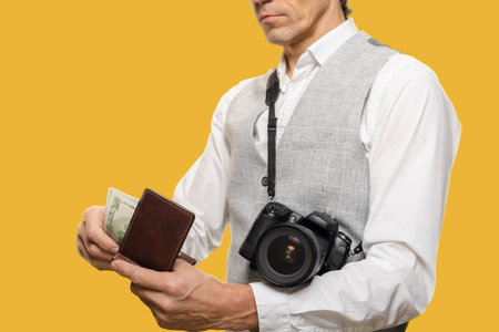 Young man with modern digital camera holding money for photographing, closeup photo, The currency serves as a tangible symbol of the photographers successful endeavors,の写真素材