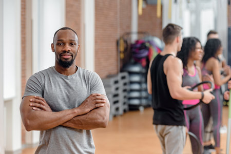 Young african man working out with diverse active people in gym. Vibrant African male engaging in a workout session with a diverse crowd of active individuals in a gymnasium.の写真素材