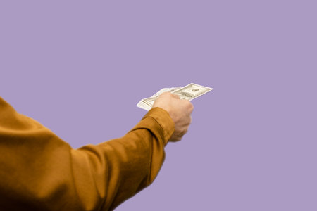 Male hand stretching pile of dollars showing his income on purple background, This striking image...