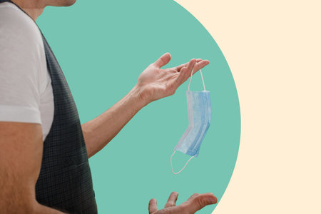 Closeup of man taking off used medical protective mask, Mask off: A man removes his sanitary mask,...
