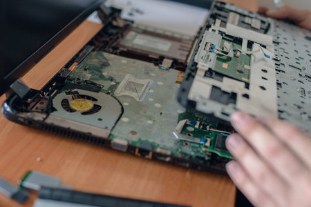 Closeup of specialist hands cleaning old laptop from dust, Laptop TLC: Skilled technician provides...