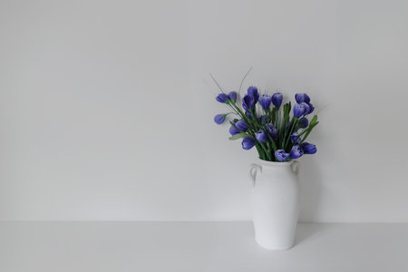 Beautiful elegant floral composition with blue crocus flowers in vase on white wall background, Elegant floral arrangement in a vase, graced by soft wall lightingの写真素材