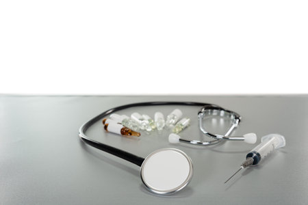 a stethoscope enveloping several ampoules and a syringe next to it on a gray table with a copy space backgroundの写真素材