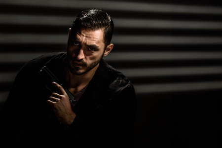 Studio portrait of bearded young man with gun dressed as secret agent, Raw power: A dark and...