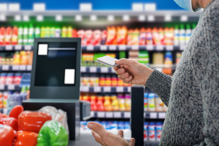 Closeup photo of male buyer using credit card at supermarket self-service cash register. Versatile options: Payment card terminals from diverse banks available at the supermarket checkoutの写真素材